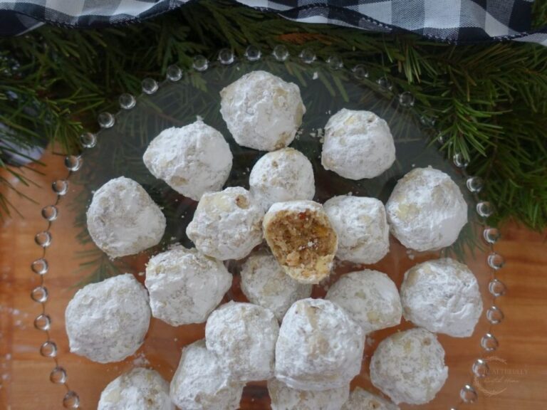 pecan meltaways on a cake stand with a fir tree branch in background with one cookie bitten