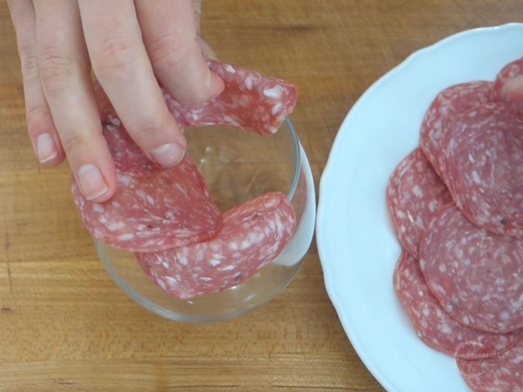 placing salami on a glass to make a salami rose