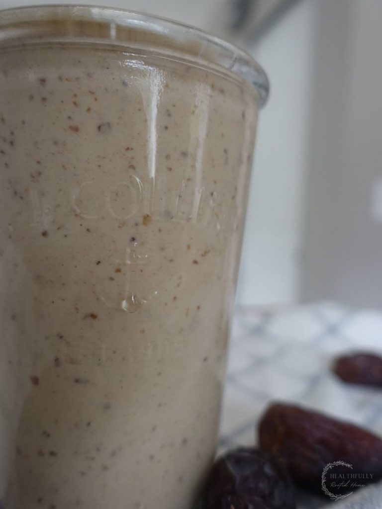 dates milkshake in a drinking glass with a straw and dates surrounding