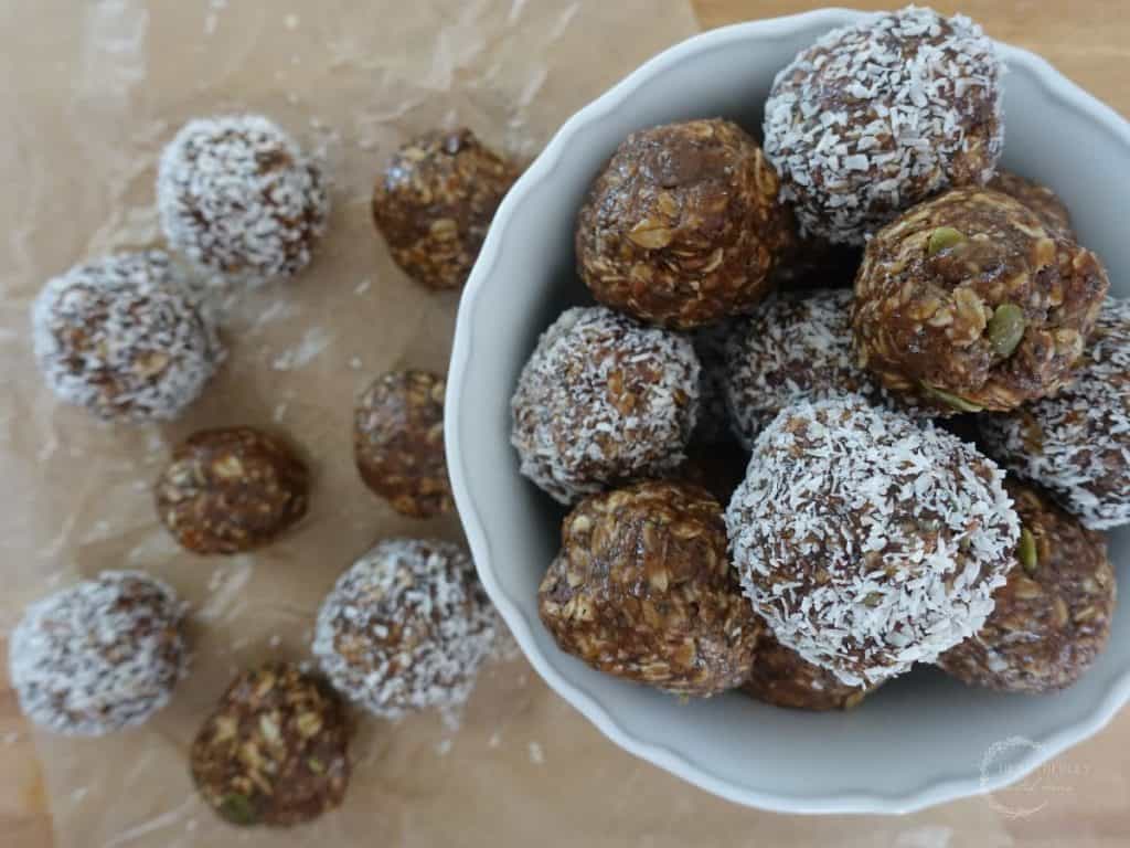 boobie balls stacked on top of eachother in a bowl with some on the outside of the bowl on top of parchment paper