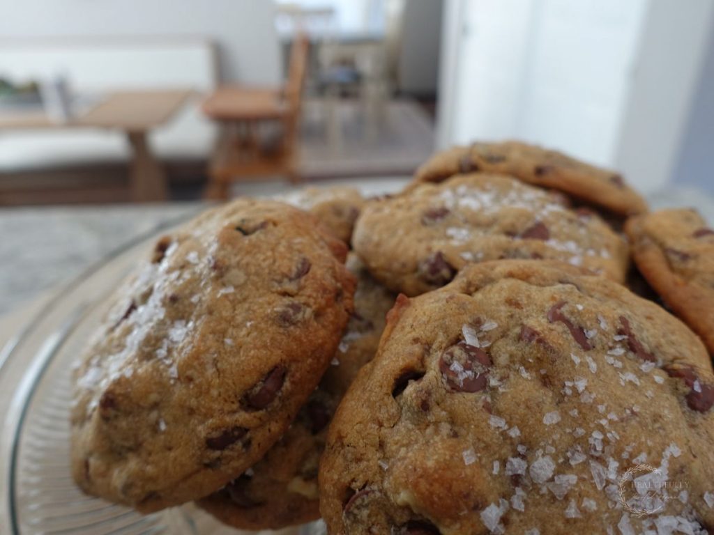 close up of boobie biscuits placed on a cake stand with a high chair in the background showing the detail of the cookies and the salt on top