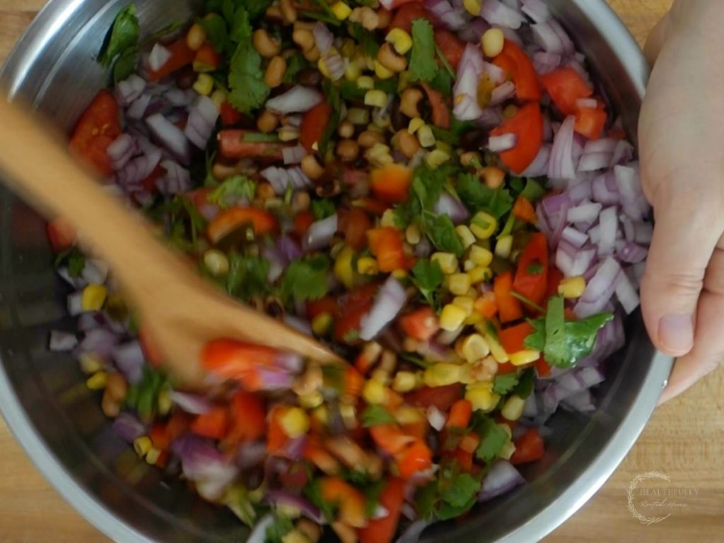 stirring mexican caviar with a wooden spoon in a large bowl