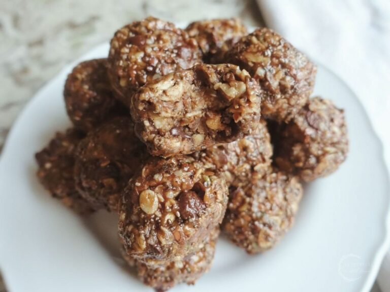 peanut butter bliss balls in a pyramid on a white plate one with a bite taken out