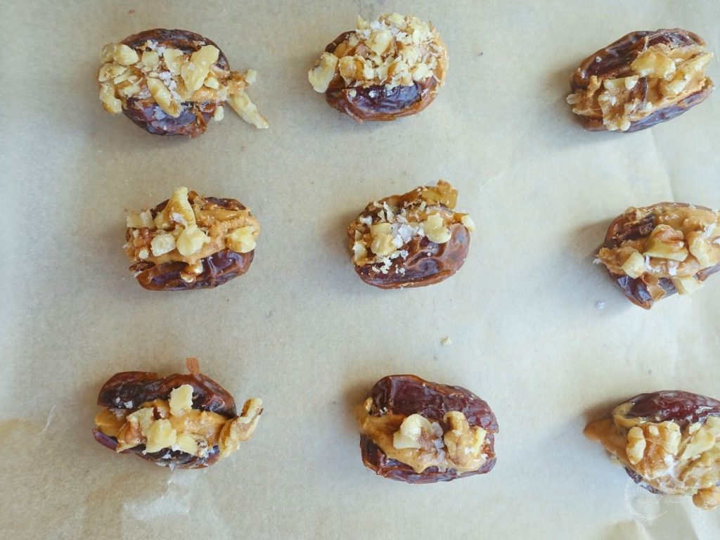 stuffed dates lined up on a parchment lined baking sheet