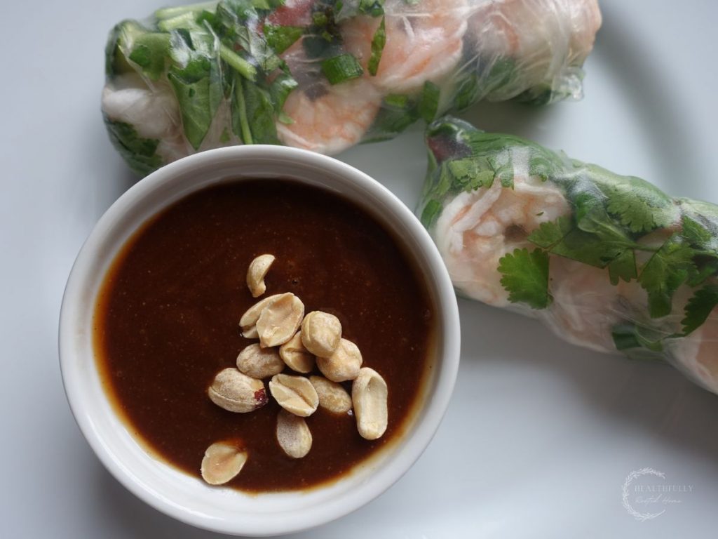 hoisin peanut sauce next to fresh spring rolls on a white plate