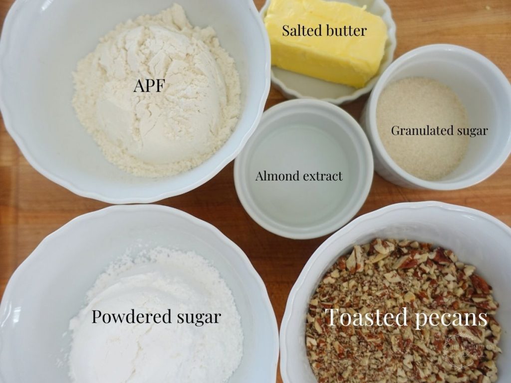 ingredients in white bowls on a wooden cutting board labeled with what they are