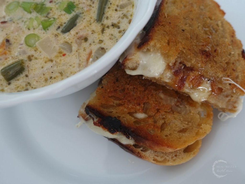 provolone grilled cheese sandwich cut in half snuggled up next to a bowl of soup