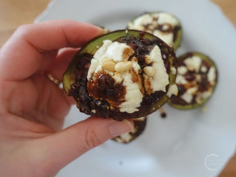 holding up a stuffed roasted avocado above a white plate