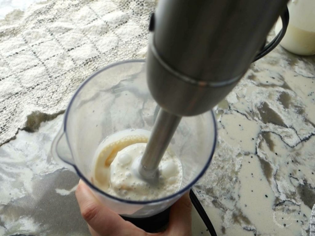 blending ingredients for salted caramel cold foam with an immersion blender