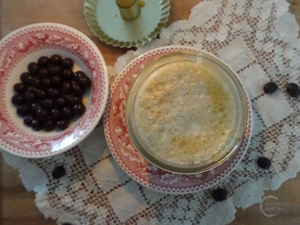 top view of the frothy salted caramel cold foam with a bowl of chocolate covered espresso beans next to it in a festive red bowl