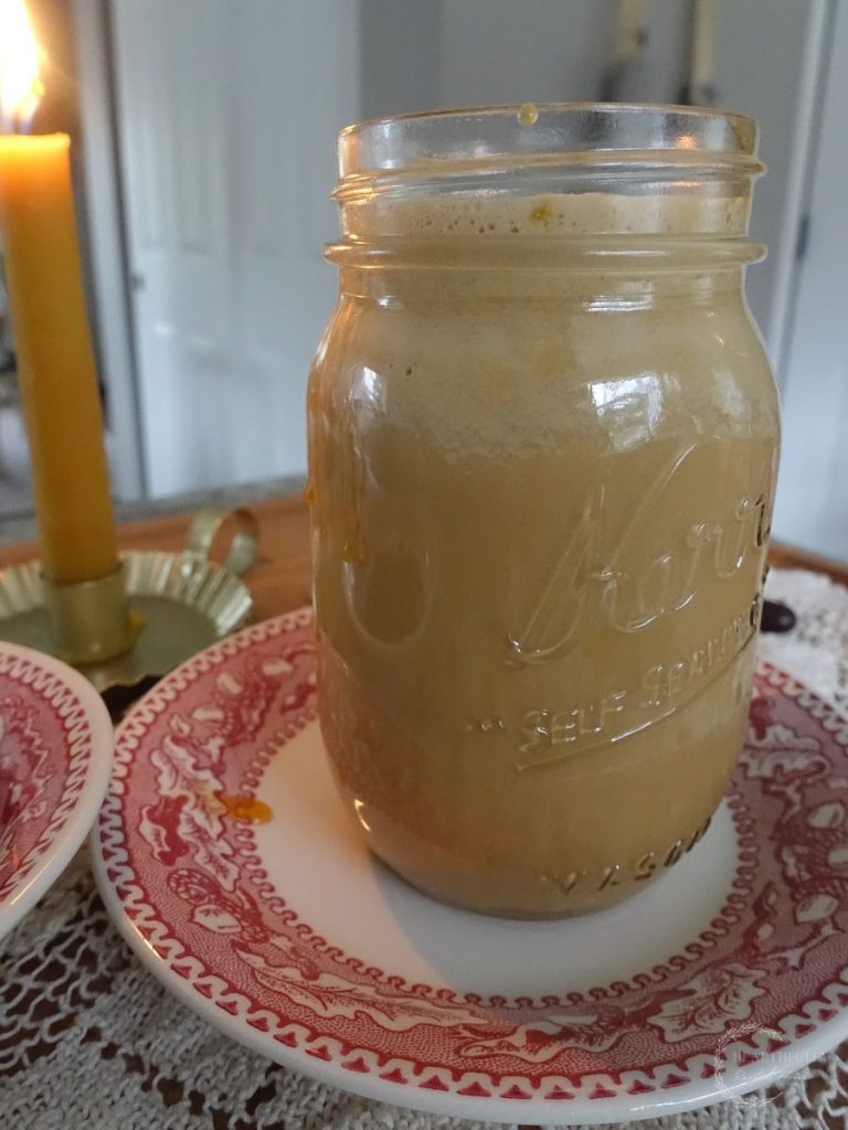 easy salted caramel cold foam cold brew with a candle in the background and red plates underneath