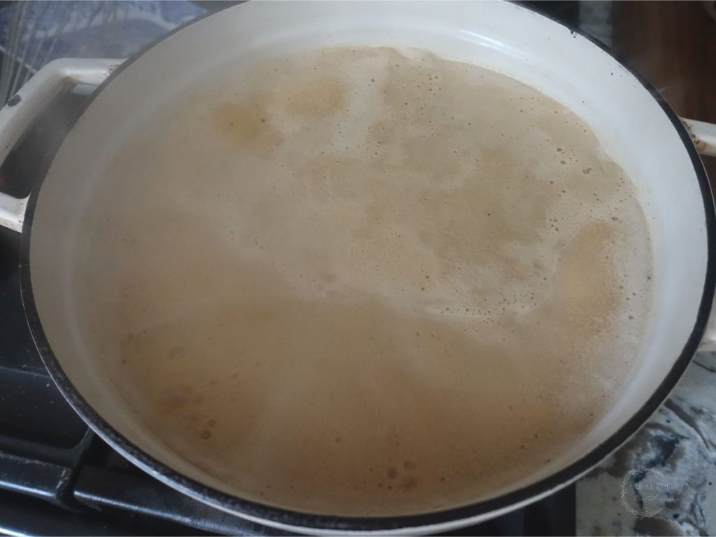 boiling milk and coconut sugar in a white dutch oven looking foamy