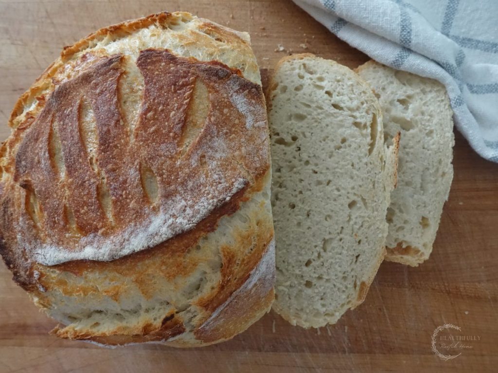 sourdough discard loaf with two slices cut from it on a wooden cutting board