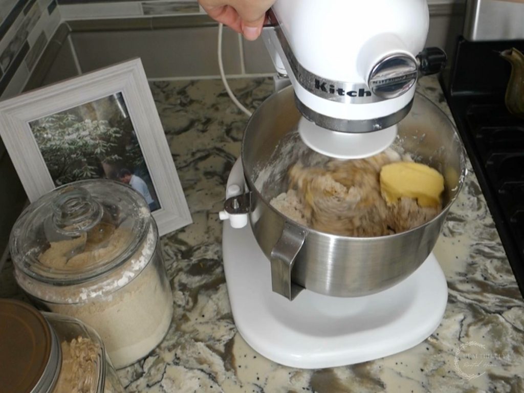 adding butter one tablespoon at a time to the sourdough babka dough in the stand mixer fitted with the dough hook attachment