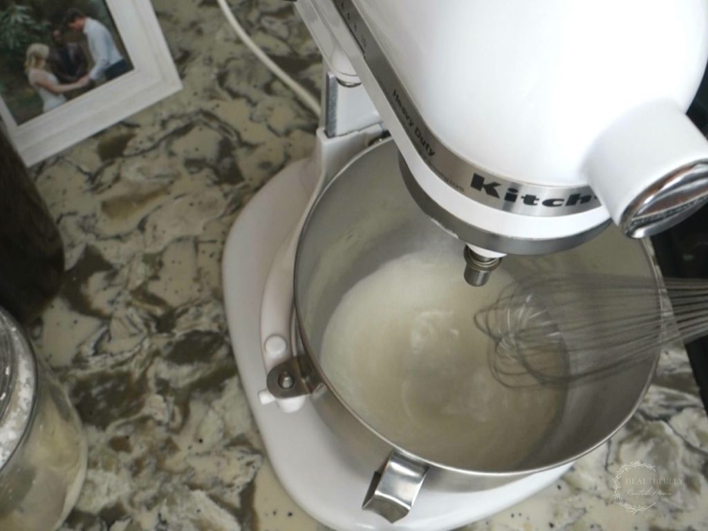 whisking warm water and yeast in the bowl of a stand mixer