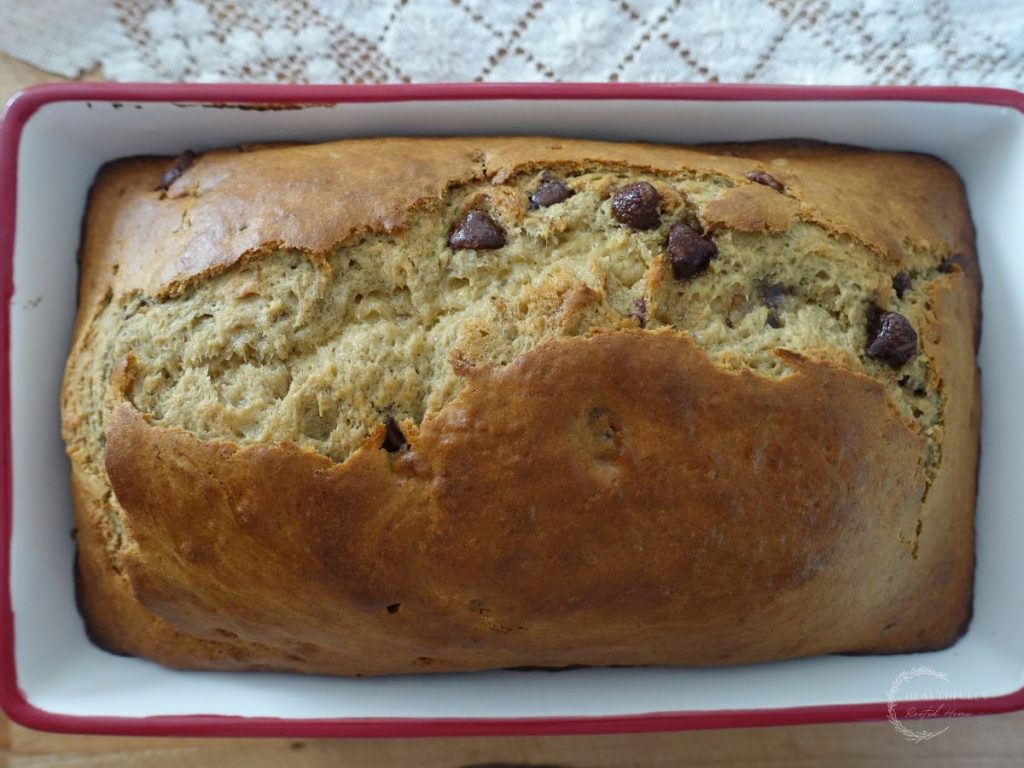 baked sourdough discard banana bread in a loaf pan with a lace doily underneath