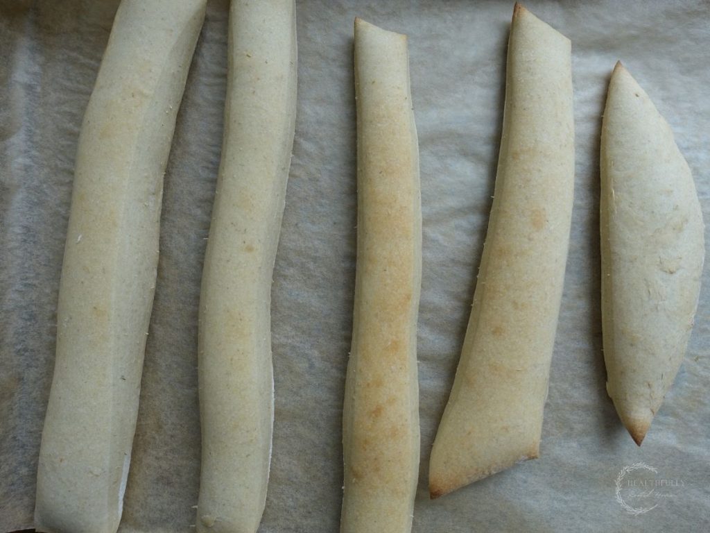 slightly golden brown sourdough breadsticks after baking on a parchment lined baking sheet
