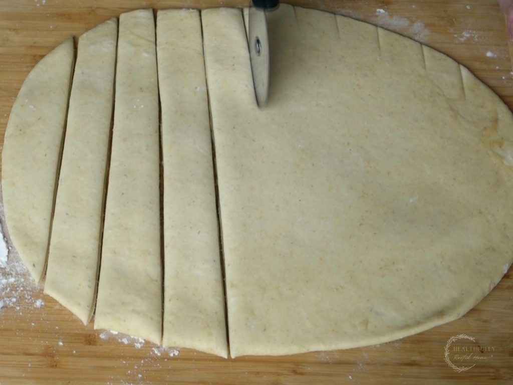 using a pizza cutter to cut into dough to make sourdough breadsticks