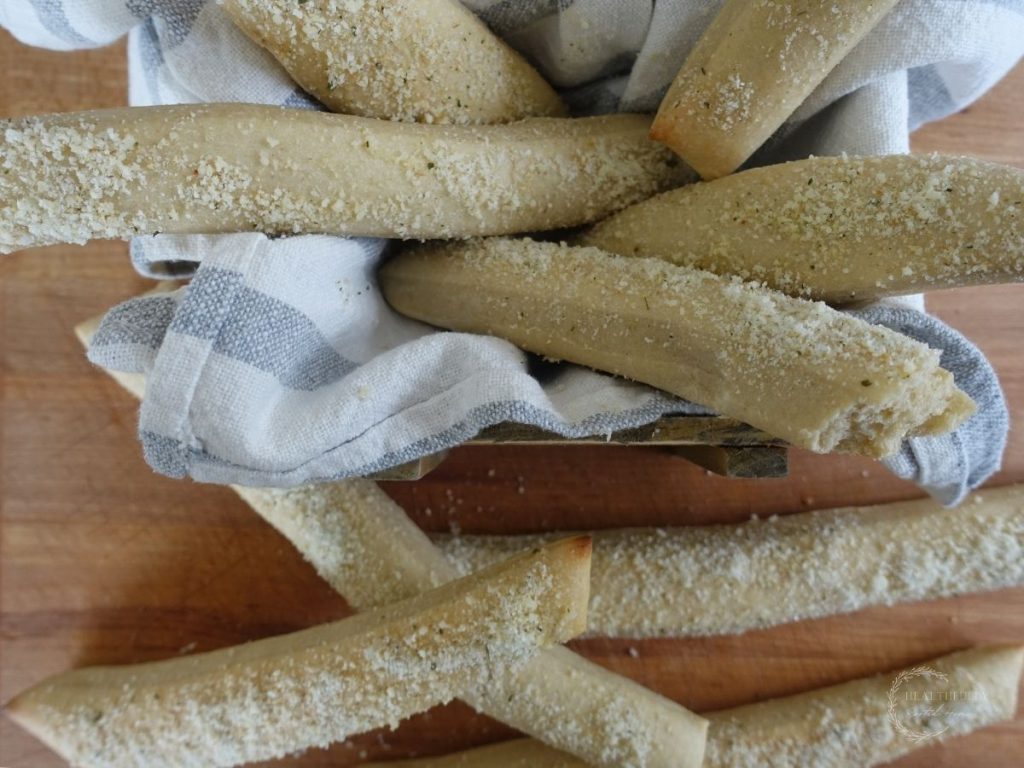 a bunch of sourdough breadsticks in a wooden crate lined with a ticking striped tea towel