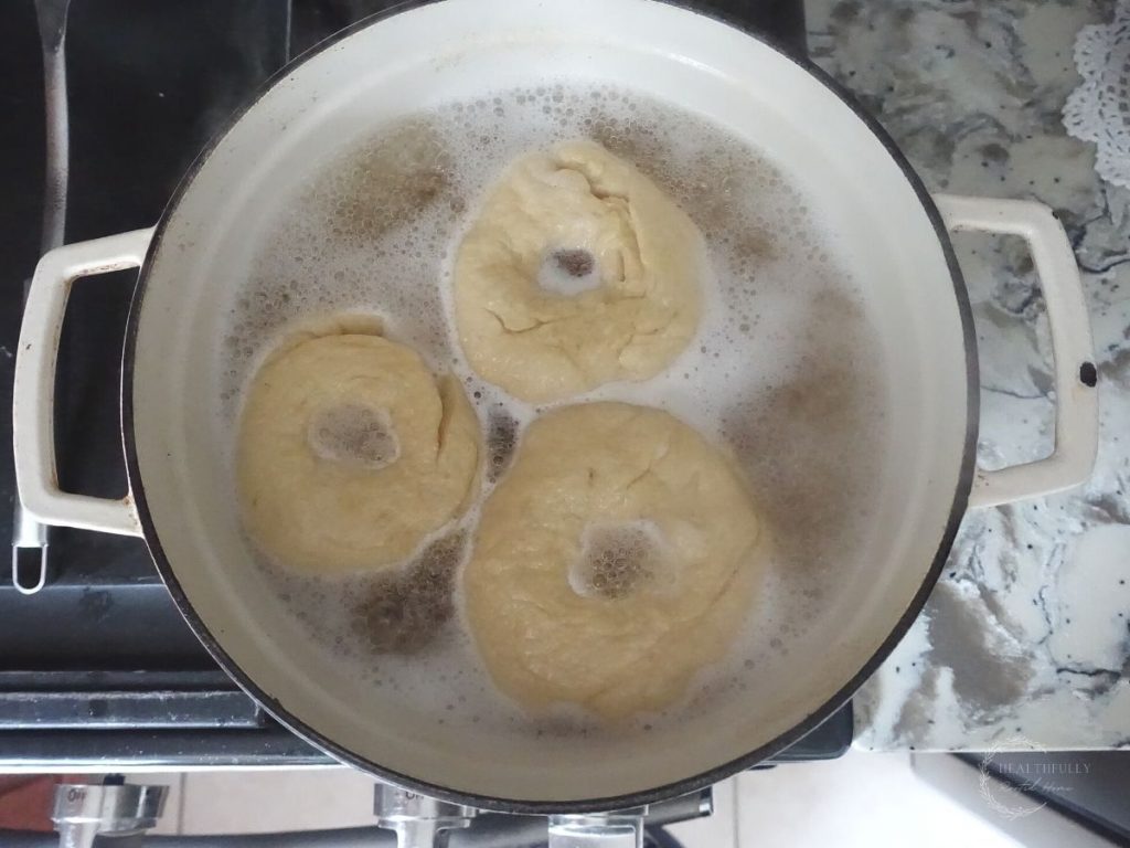 bagels being boiled in a pot of boiling water