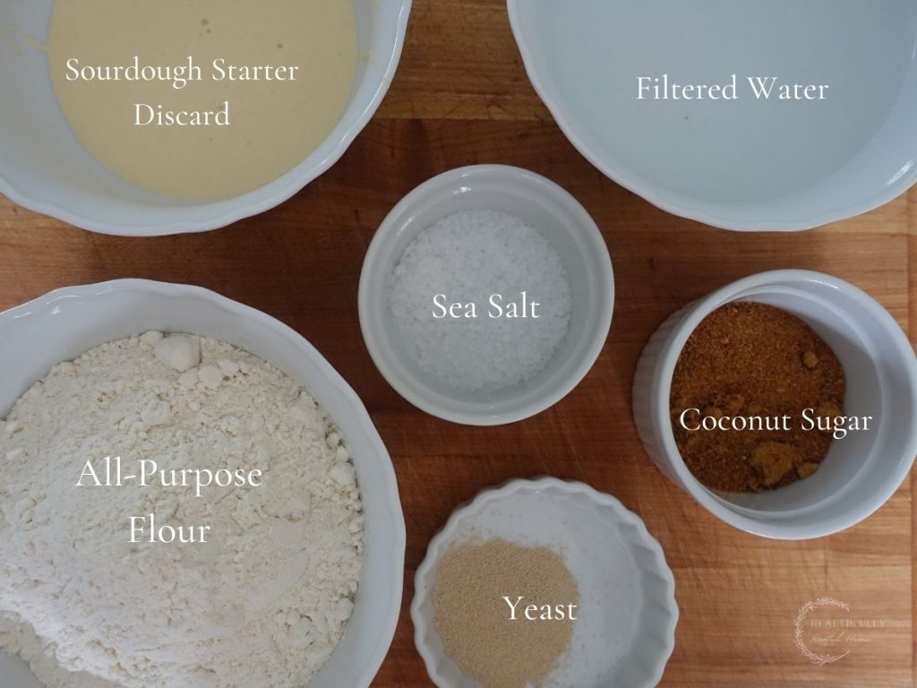 ingredients to make sourdough discard bagels in white bowls with labels saying what they are