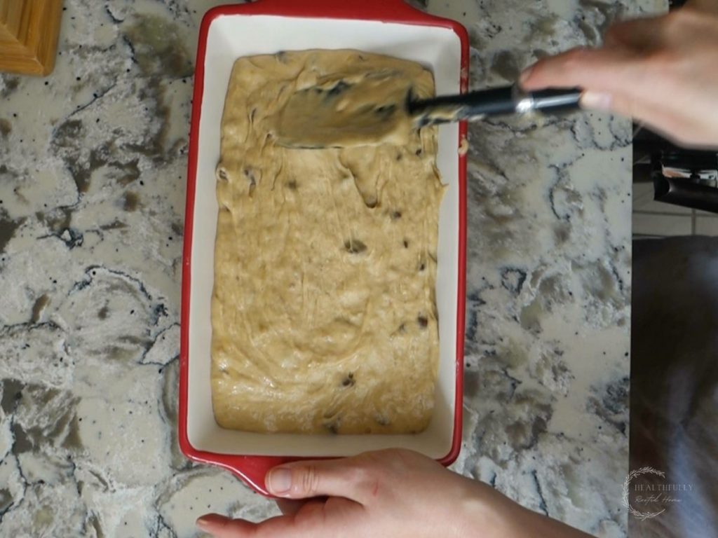pouring the sourdough discard banana bread batter into a loaf pan and smoothing out the top with a spatula