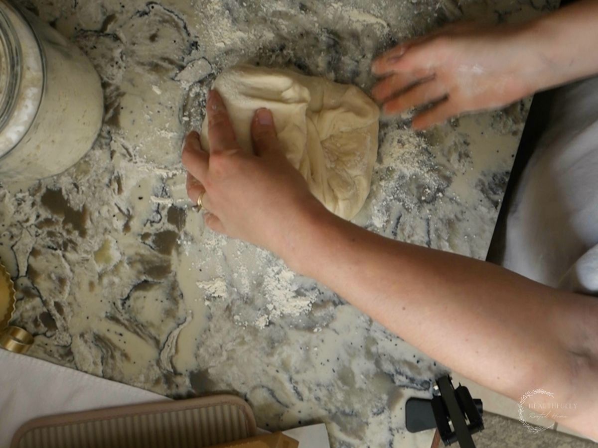 beginning to shape the dough of sourdough discard bread on a floured surface