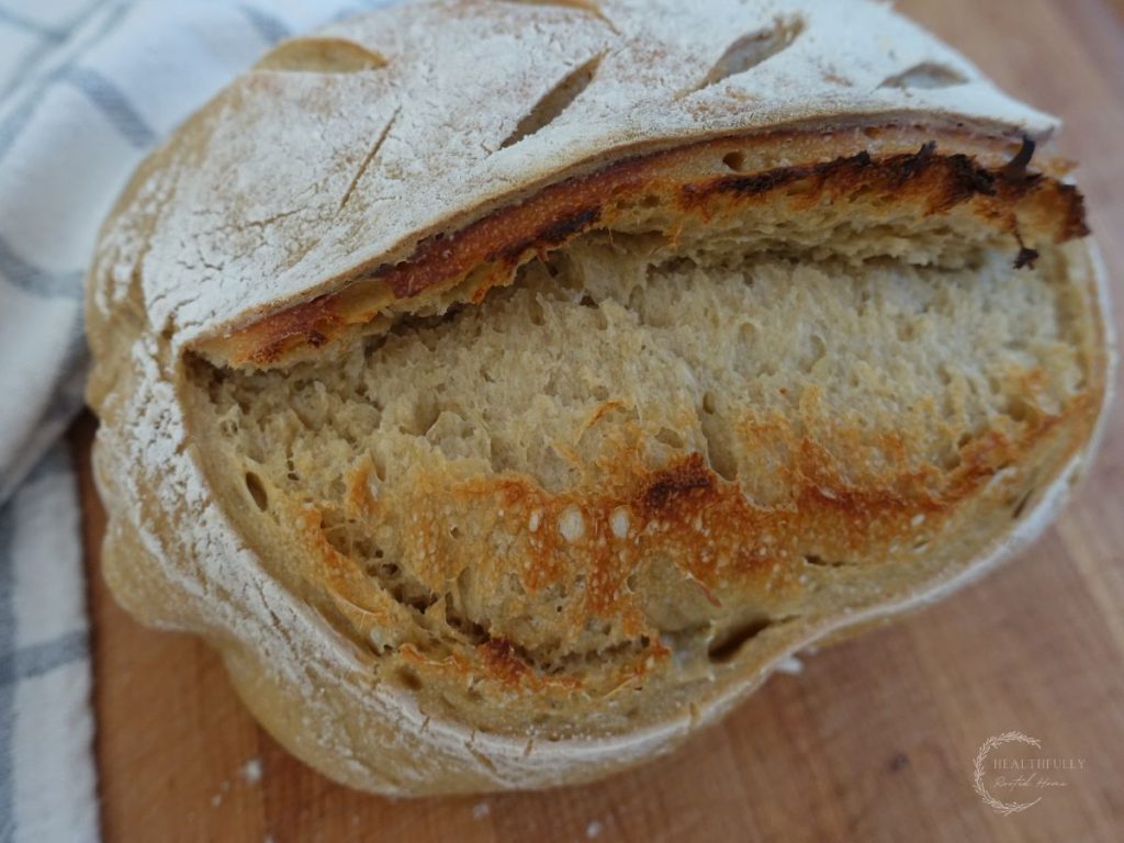 sourdough discard bread with a large ear next to a tea towel on a wooden cutting board