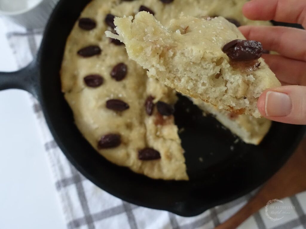 sourdough discard focaccia bread slice showing the inner crumb with the skillet of the entire loaf in the background