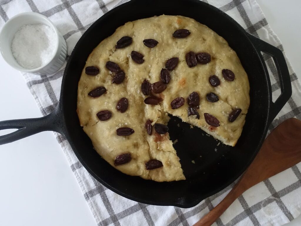 sourdough discard focaccia bread in a cast iron skillet with a slice taken out of it