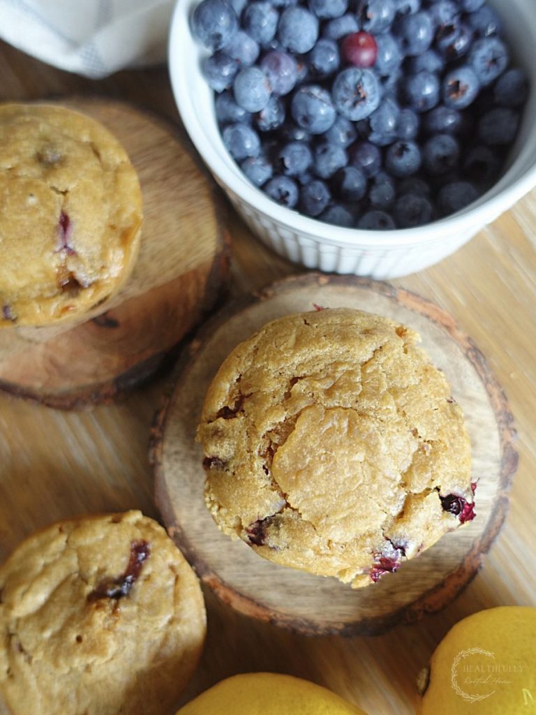 lemon blueberry sourdough discard muffins with a bowl of blueberries on the side and lemons next to the muffins