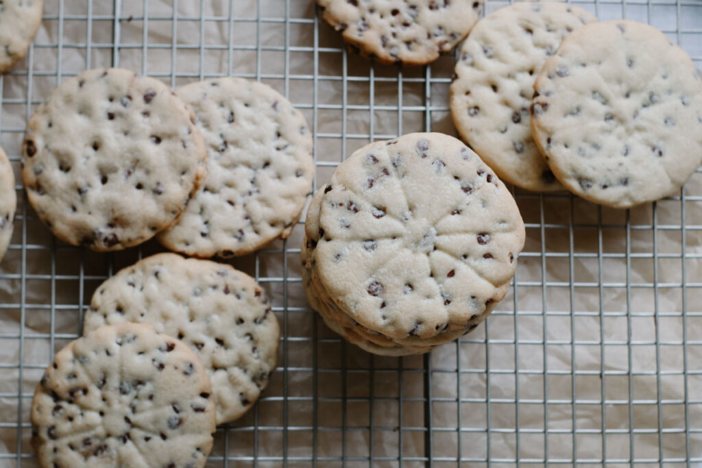scattered chocolate chip sugar cookies on a wire cooling rack with a few stacked on top of eachother