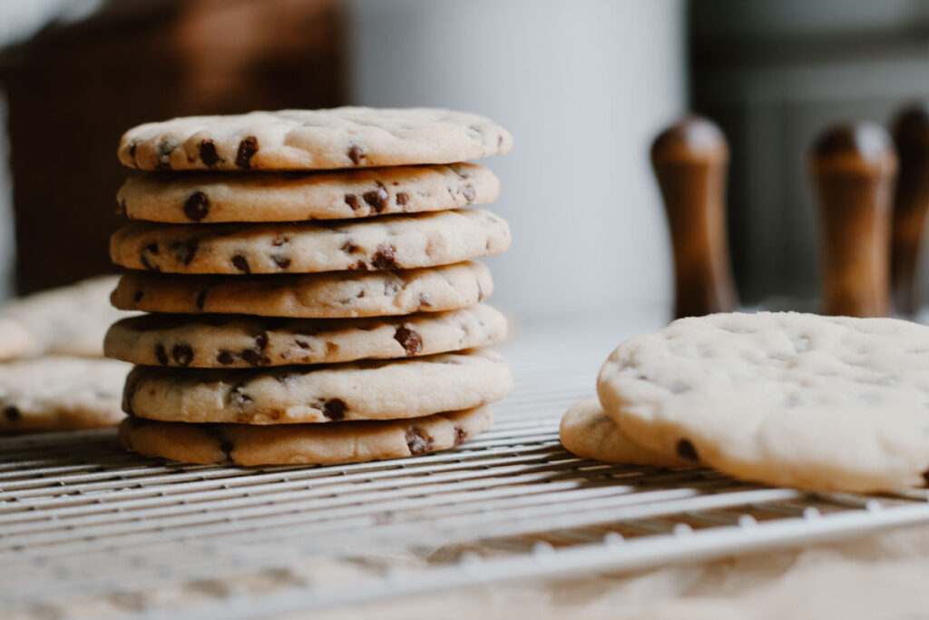 stacked up sugar cookies with chocolate chips with cookie stamps in the background