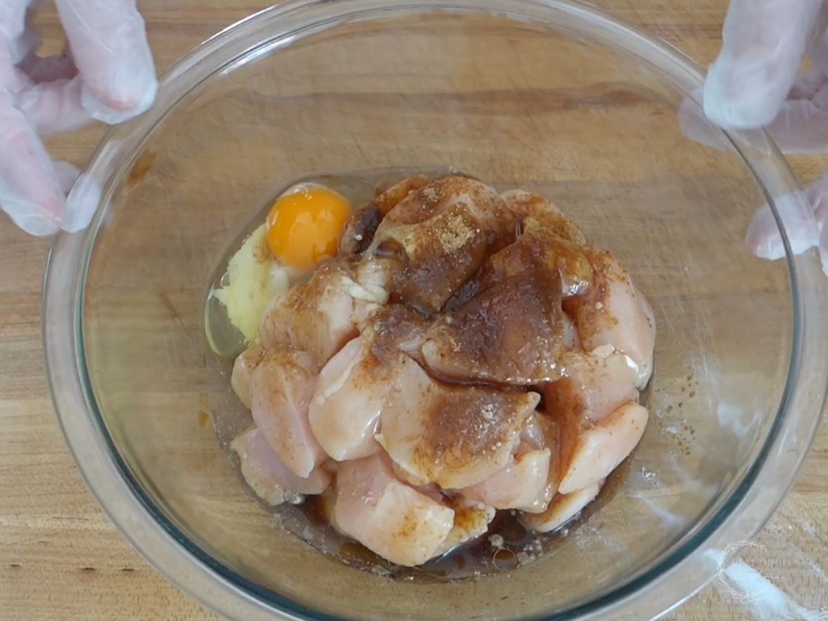 diced chicken breast ina glass bowl with the ingredients for the marinade on top