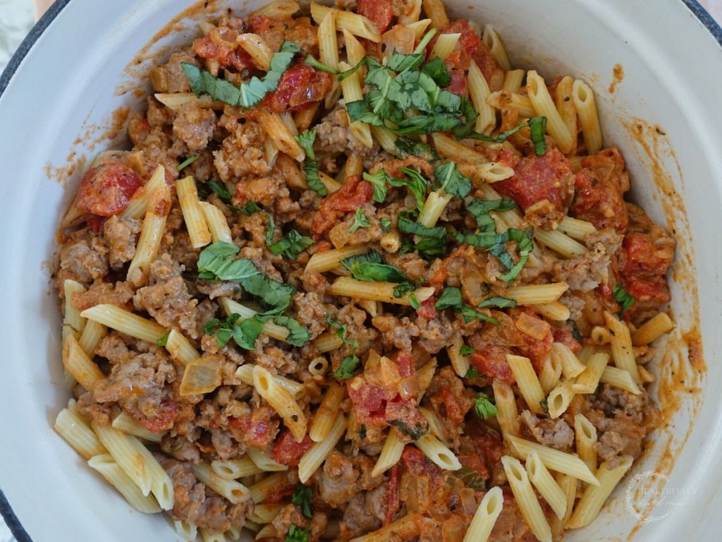 pasta served with tomato mascarpone sauce and italian sausage in a cast iron dutch oven