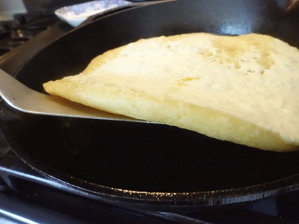 using a spatula to lift up the sourdough discard flatbread