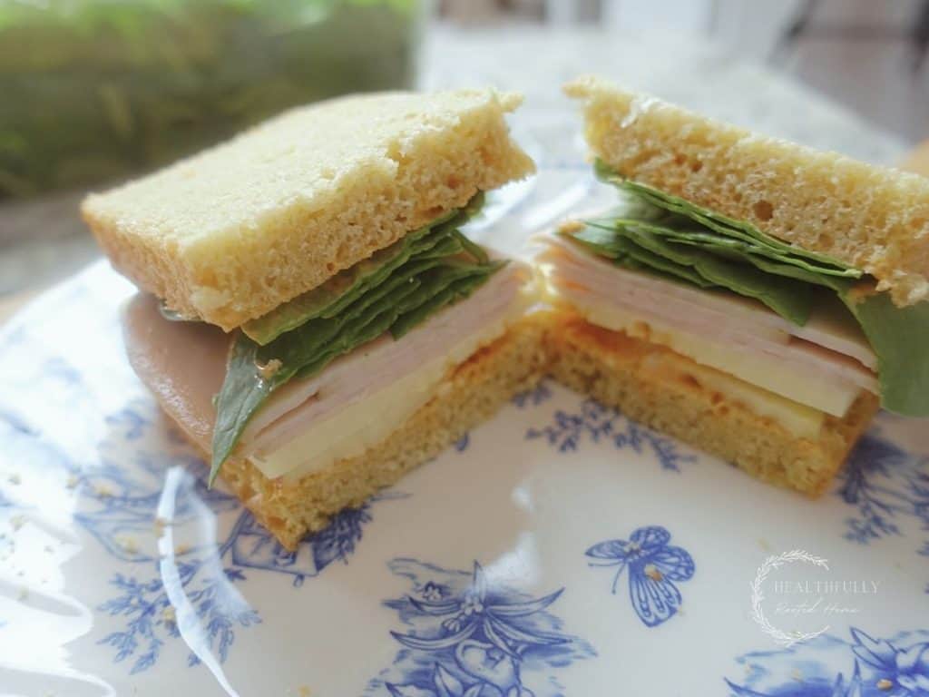 deli sandwich cut in half with spinach turkey and bread showing on a white and blue plate