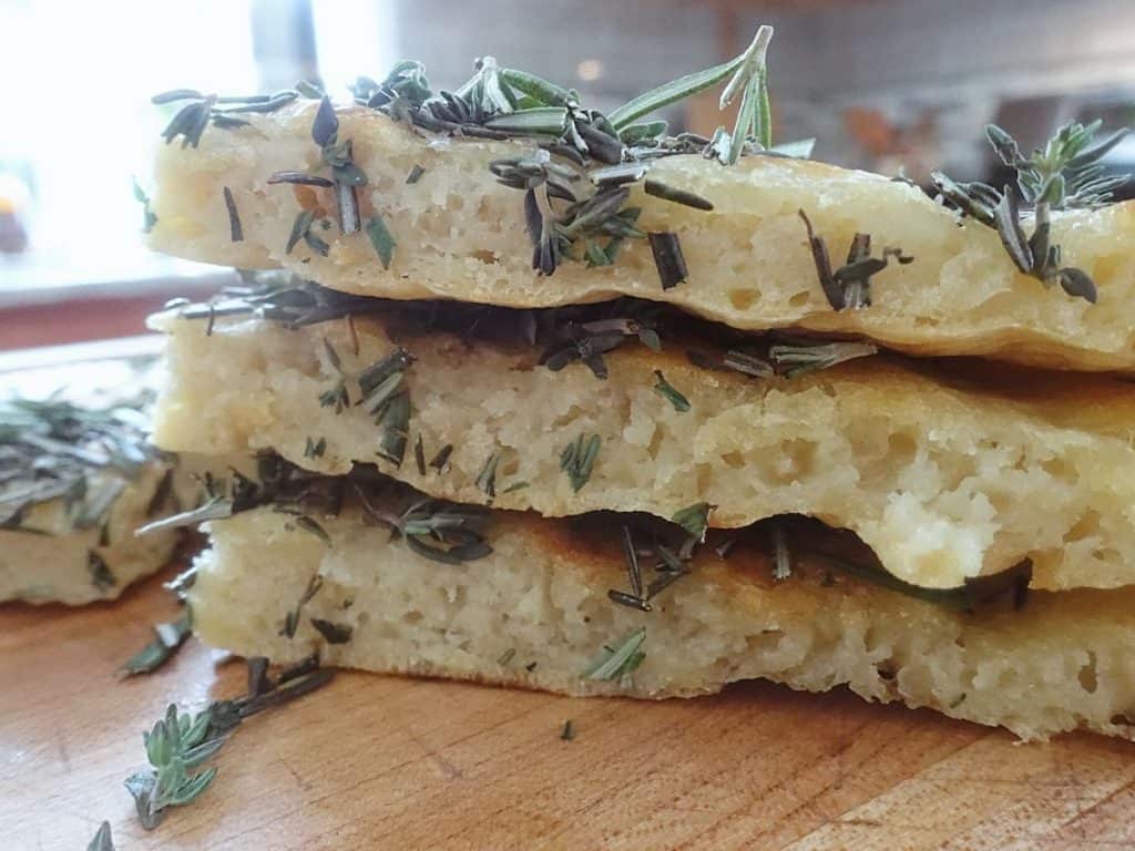 sourdough discard flatbread cut into triangles stacked on top of eachother with fresh herbs