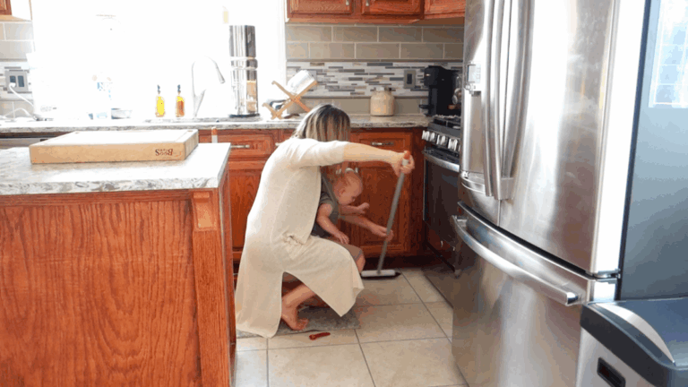 sweeping in the corners while doing autumn clean while babywearing in a boba wrap