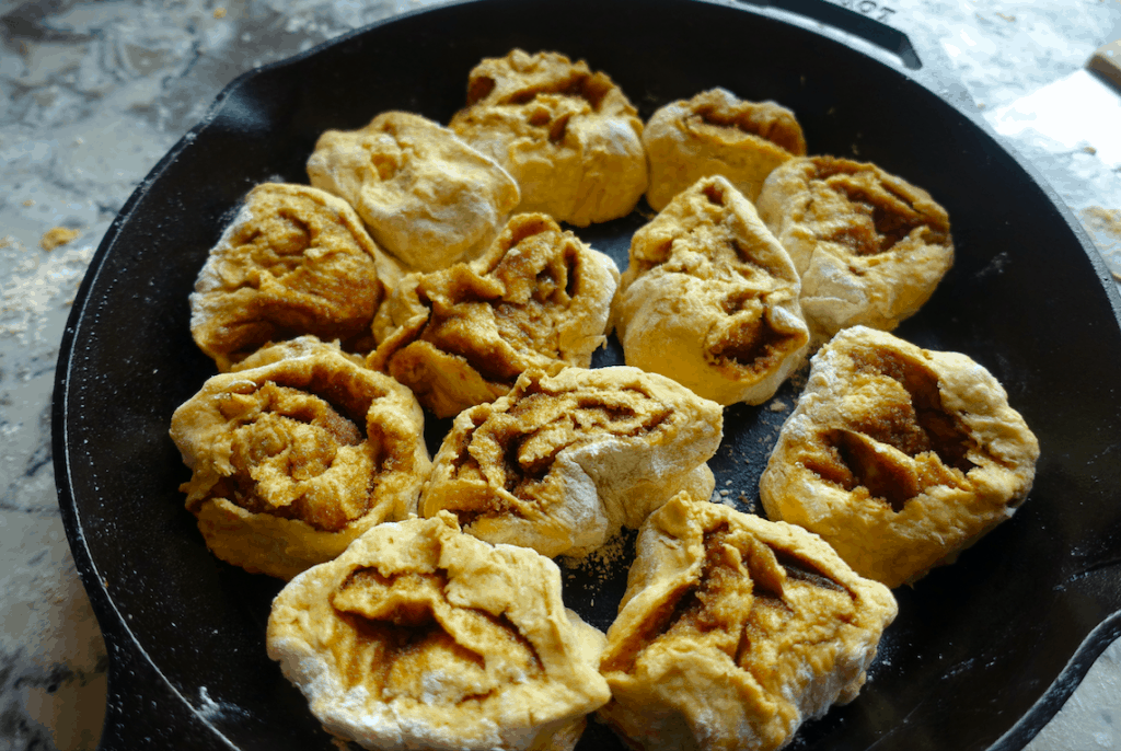 pumpkin sourdough cinnamon rolls in a cast iron skillet ready to be baked