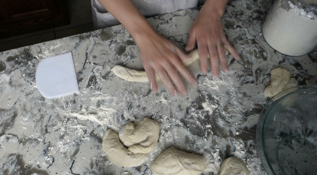 rolling out sourdough pretzel dough into a long rope