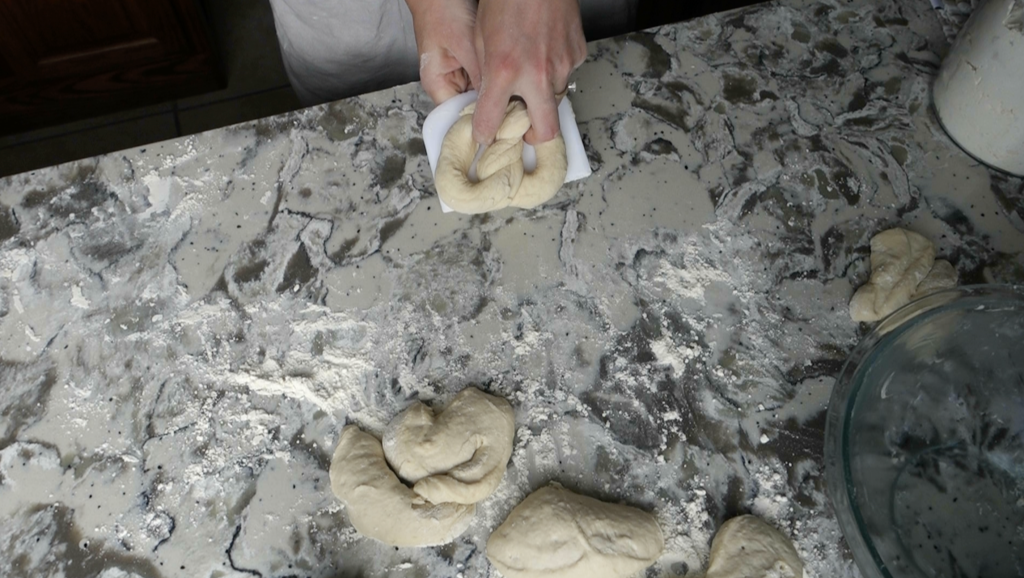 lifting a sourdough pretzel off the work surface