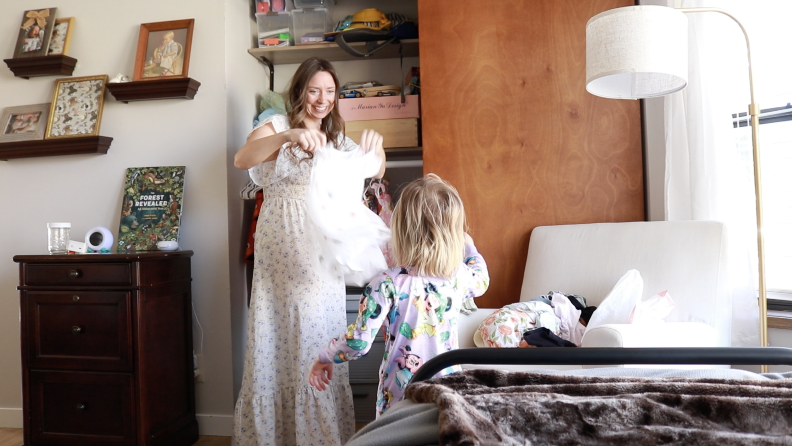A Christian homemaker holds up her dress for her daughter to wear.