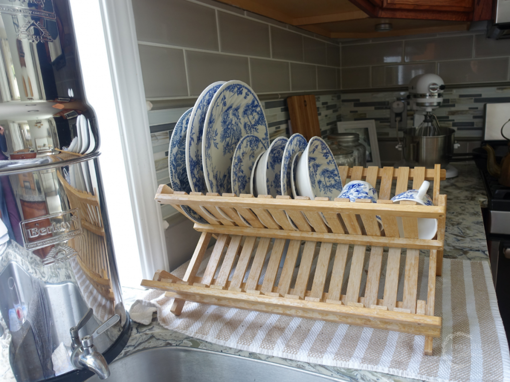 Berkey water filter next to a dish drying rack with blue and white china drying