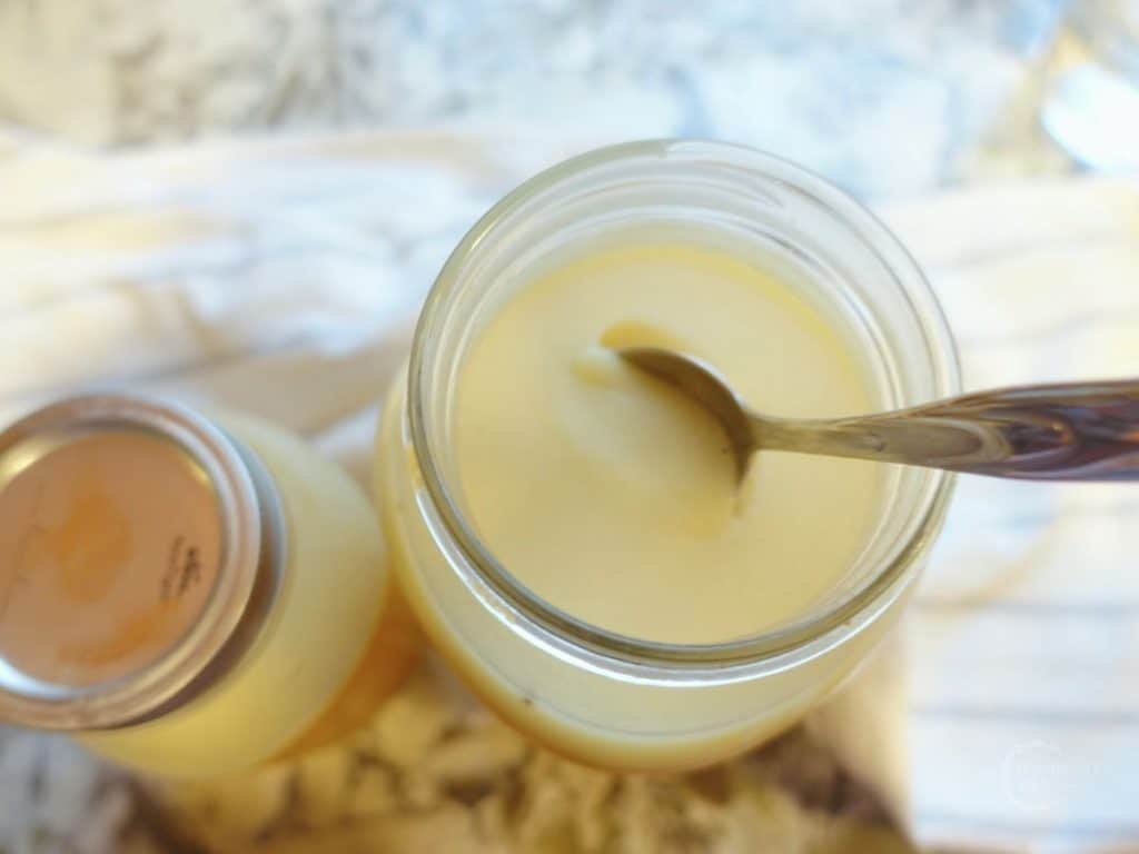 two jars of chicken collagen soup one with a spoon in it so you can see that it has gelled