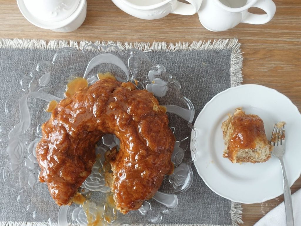 a birds eye view of sourdough pull apart bread with a plate and a piece of bread on the plate next to it