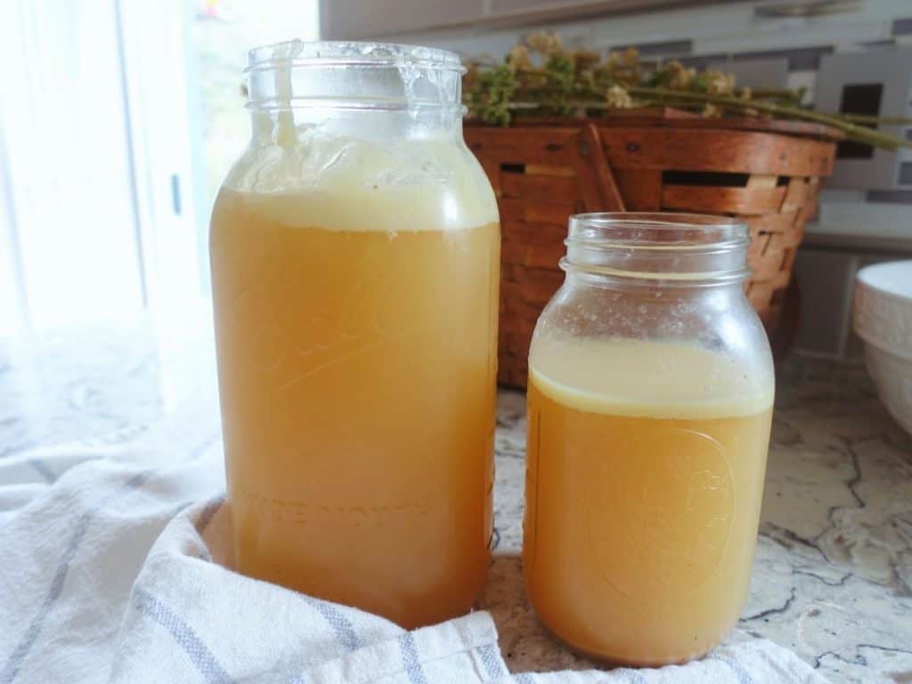 two jars of chicken collagen soup behind a tea towel with basket in background