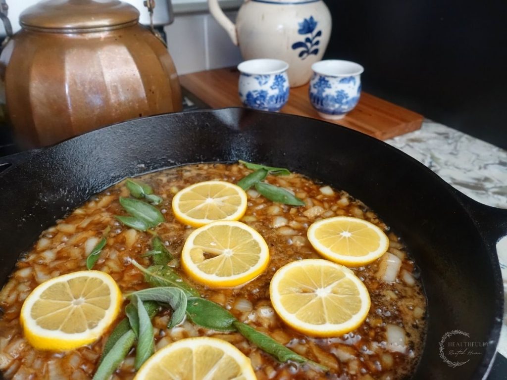 lemon slices sage leaves and onions in a cast iron skillet simmering 