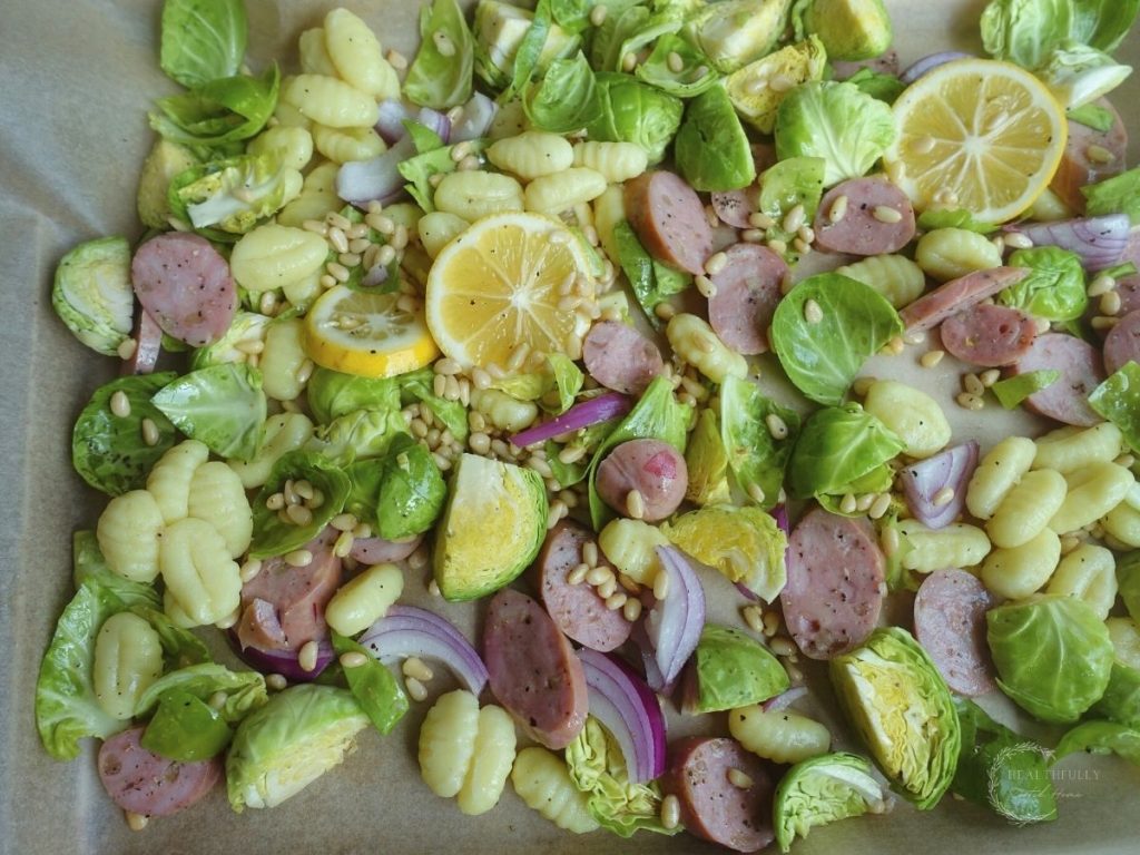 brussels sprouts gnocchi lemon pine nuts and red onion on a sheet pan lined with parchment paper
