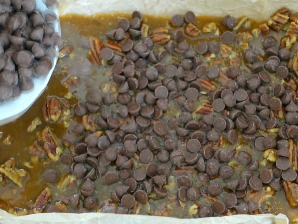 sprinkling chocolate chips overtop toffee